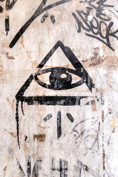 Illuminati logo painted on the wall. "All seeing eye" of God in sacred geometry triangle. Masonry and Illuminati symbol in triangle with light ray.