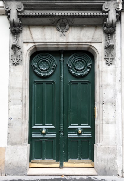 Dark green wooden door in old building facade. Paris, France