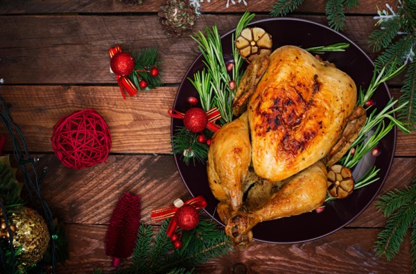 Baked turkey or chicken. The Christmas table is served with a turkey, decorated with bright tinsel and candles. Fried chicken, table. Christmas dinner