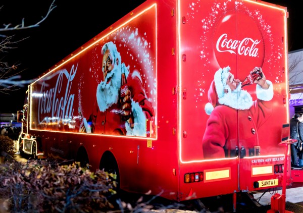 Coca-Cola Christmas truck at night in the UK depicting traditional Santa Claus or Father Christmas holding a bottle of Coke