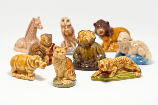 Close up of a collection of Wade Whimsies, small porcelain animal figurines popular with collectors since the 1950s, against a white background.