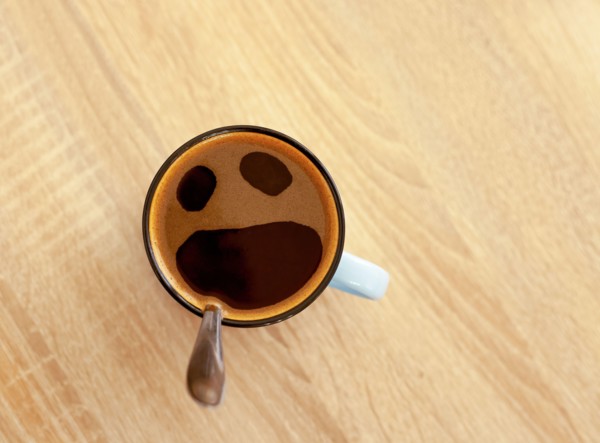 Coffee cup with funny screaming in fear face, top view. Open crying mouth in mug on table background. Shocked, stressed, angry, scared and furious foa
