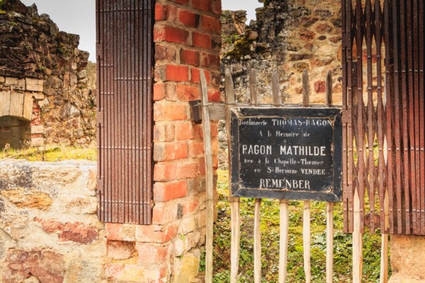 ORADOUR SUR GLANE, FRANCE - December 03, 2017 : commemorative tag on the remains in ruins of the THOMAS-RAGON bakery where it is written - In memory o