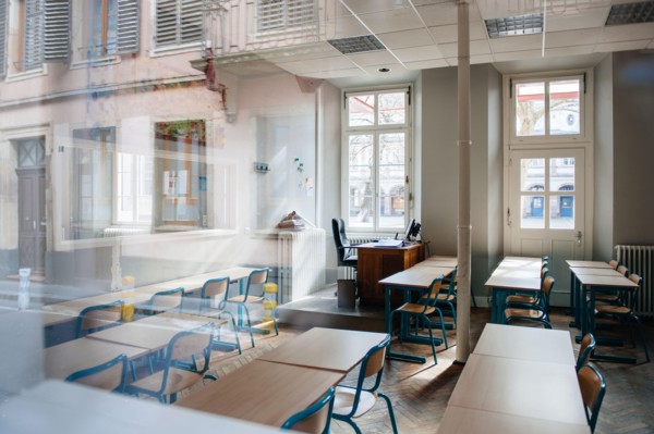 View from the street of large school classroom with empty seats - reflections of city in the window