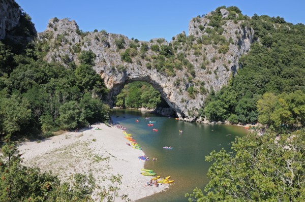 Pont d’Arc rock archway over the Ardeche river Gorges d’Ardeche Gard France with canoes and tourists sunbathing