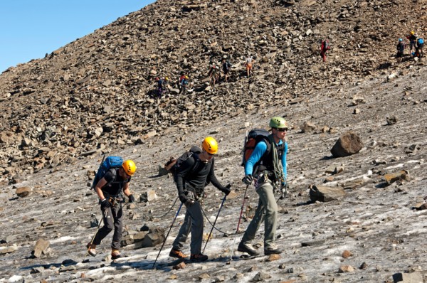 Three mountaineers on the way to the Mont Blanc peak crossing an ice field near the Tete-Rousse mountain hut, Chamonix, France