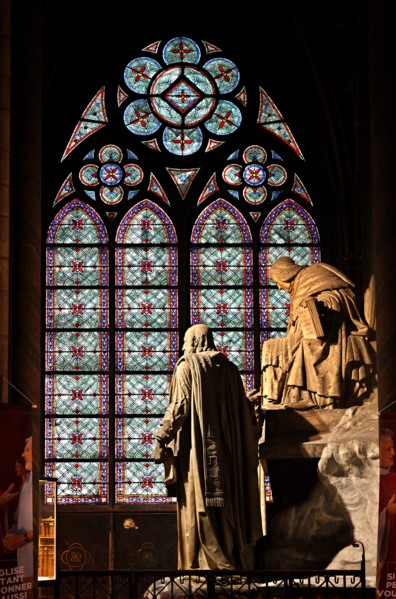 Beautiful stained glass window and sculpture inside the Notre Dame Cathedral, Paris, France.