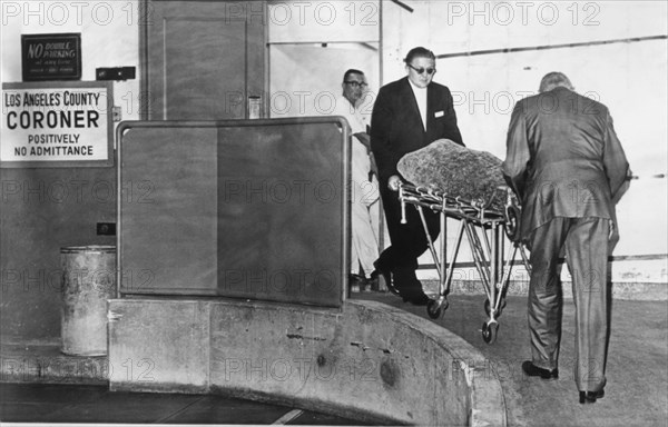 1962 , 6 august , LOS ANGELES , USA : The body of american actress MARILYN MONROE ( 1926 - 1962 ) wrapped in blankets , is wheeled from the Los Angeles County Morgue and en route to the Westwood Villa...