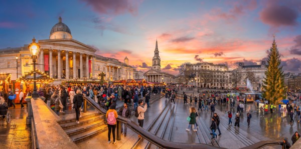 London, UK - November 25, 2023: Twilight at Trafalgar Square with golden sunset hues, reflecting on wet streets—capturing London's vibrant evening cha