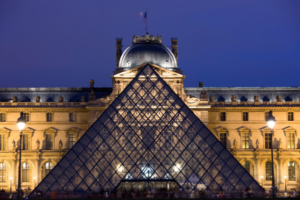 The Louvre Museum illuminated glass pyramid entrance Paris France