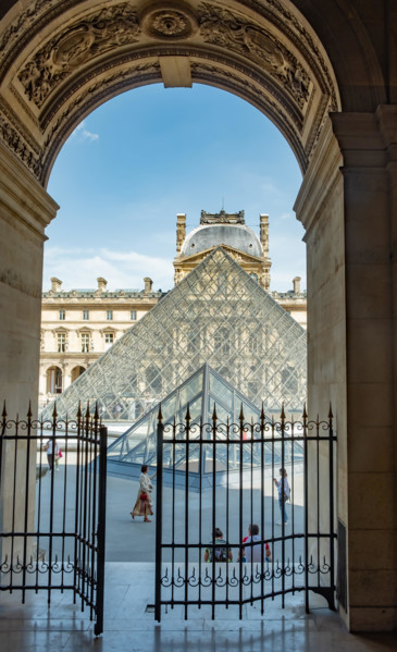 Looking through an archway towards the Pyramid at the Louvre in Paris France.  A former fortress and palace, The Louvre is the largest art museum in t