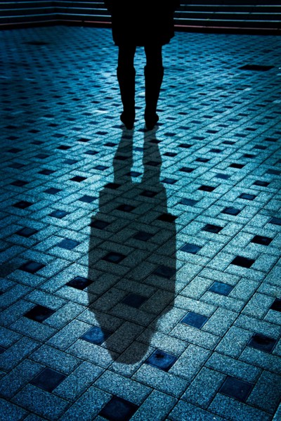 mysterious woman in black coat and boots with shadow