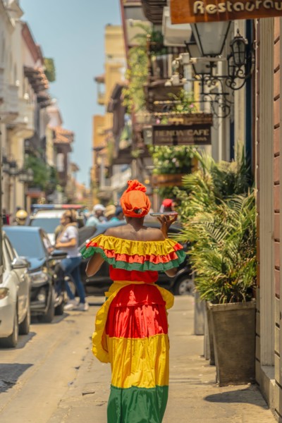 Photograph of a Colombian woman in Cartagena de Indias walking in the Palenqueras dress. Trip to Colombia. Typical colonial colors of the city