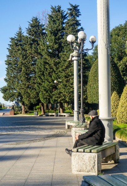A lonely man sits on a park bench. An elderly gentleman in the park. Relaxation in the park. Loneliness concept