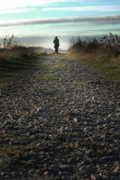 Walking a path into the distance. Back view of a woman on the horizon at the end of a path.