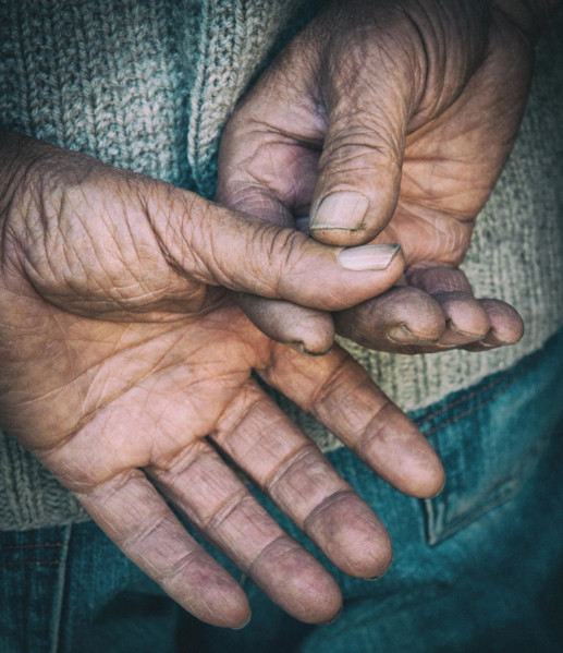 Bare senior adult hands isolated on a black background. Concept of hard worker.