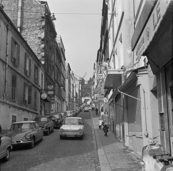 Pariser Bilder [The street life of Paris]  Rue Lepic in Montmartre, with Le Moulin de la Galette at the end of the street Annotation: Le Moulin de la Galette was a popular dance venue and figures on p...