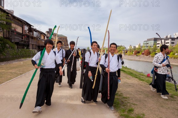 School boys carrying archery equipment, walk along the sides of the Kamo River in Gion, Kyoto, Japan.