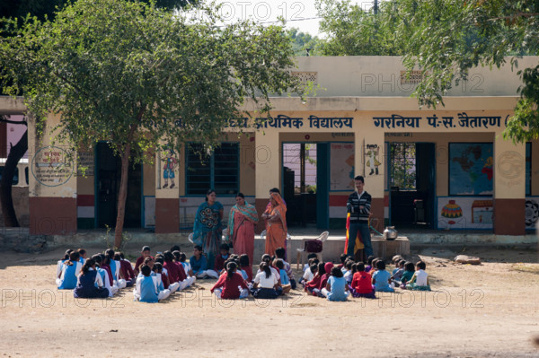 Rajasthan, India. Between Jodhpur and Jaipur. Primary school with children and teachers; lesson outside under a tree.