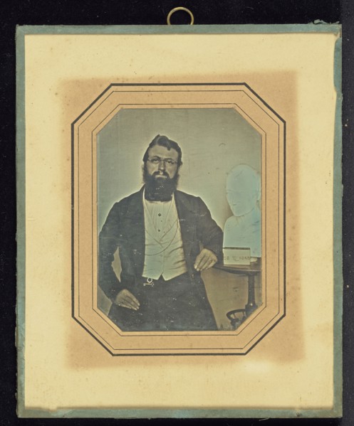 Portrait of a Bearded Man Wearing Wire-Rimmed Glasses seated next to a Bust of Voltaire by Houdon; French; July 28, 1843