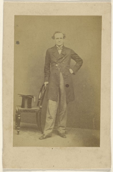 man standing, holding chair back with top hat in seat; about 1865; Albumen silver print
