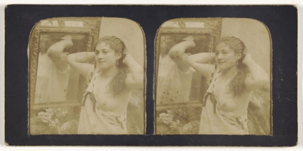 Woman before mirror with hands behind head, one breast exposed; French; 1855 - 1860; Hand-colored Albumen silver print