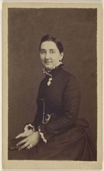 woman wearing a dark dress, holding a book, seated; 1865 - 1870; Albumen silver print