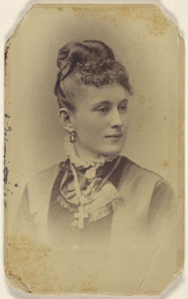 woman with her hair in a bun, crucifix around her neck, printed in vignette-style; J.B. Scholl, American, active Chicago