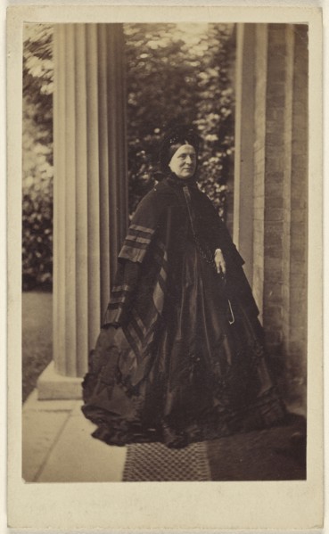elderly woman standing outside near column at house entrance; J.G. & E.G. Short, British, 1865 - 1875; Albumen silver print