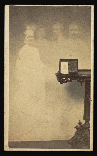Female  spirit  with three male  spirits  next to table with a cabinet card propped against an album; Attributed to William H