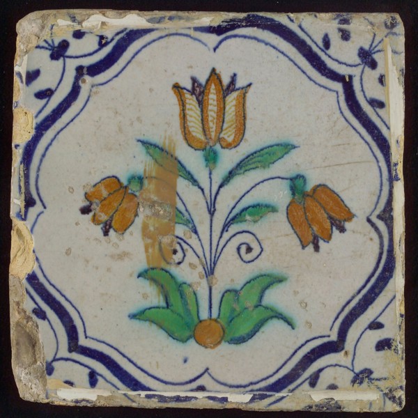 Tile, three-tier in blue, green, orange and purple on white, inside frame with accolades, corner motif, wing, wall tile
