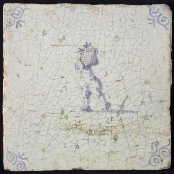 Occupation tile, blue with man crumbling with basket on the back, corner motif ox's head, wall tile tile sculpture ceramic