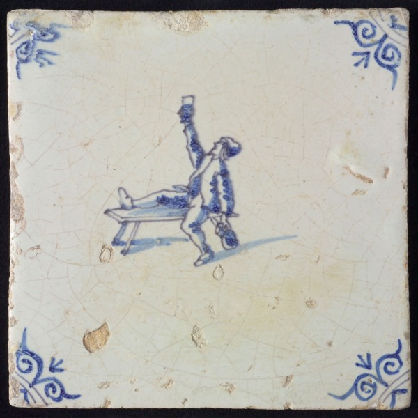 Figure tile, blue with man sitting with one leg on bench, lifting glass, another hand beer jug, corner motif oxen head, wall