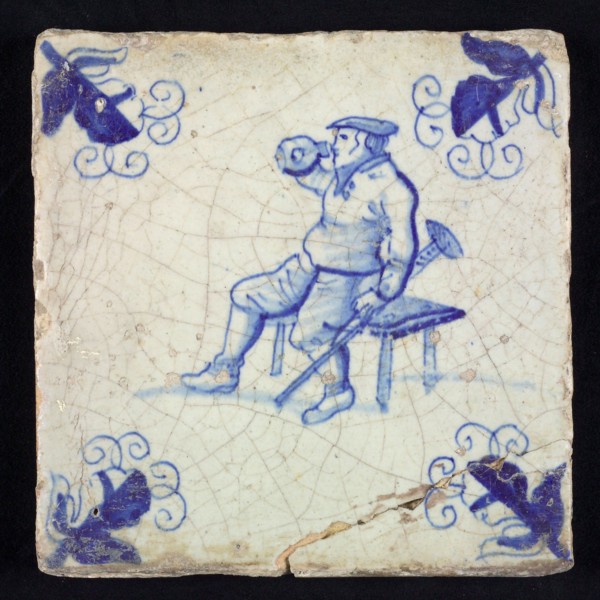 Figure tile, blue with disabled man with stool, sitting on bench, drinking from jug, corner motif, vane leaf, wall tile