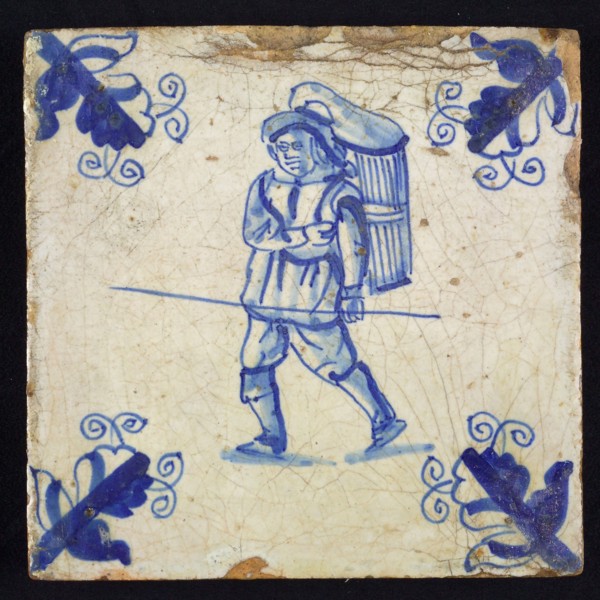 Figure tile, blue with walking man with basket or basket on the back and staff in the hand, corner motif, wall tile