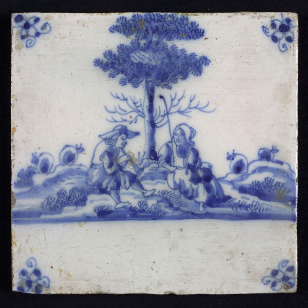 Figure tile, blue with an amiable shepherd scene with shepherd and shepherdess, sitting at tree, corner motif spider, wall tile