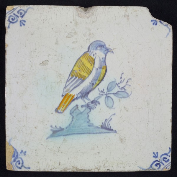 Animal tile, bird on branch to the right in yellow, orange, green and blue on white, corner pattern ossenkop, wall tile