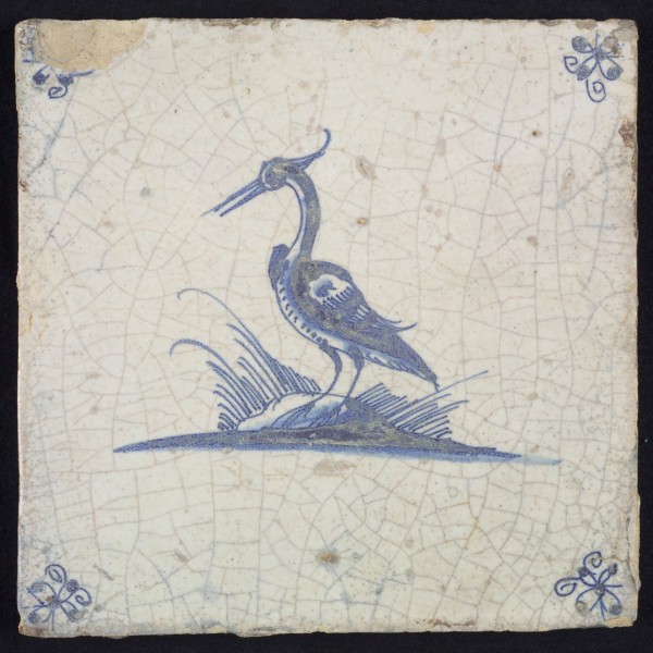 Animal tile, standing heron to the left on ground, in blue on white, corner motif spider, wall tile tile sculpture ceramic