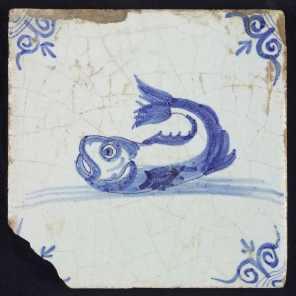 Animal tile, unknown fish in water to the left with open beak and curled tail, in blue on white, corner motif oxen head, wall