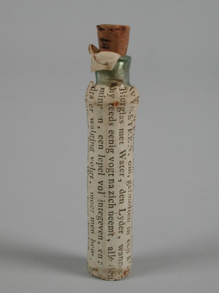 Transparent glass bottle with vomit and label In this bottle are six Greinen BRAAKWYNSTEEN, bottle holder medicine pharmacy