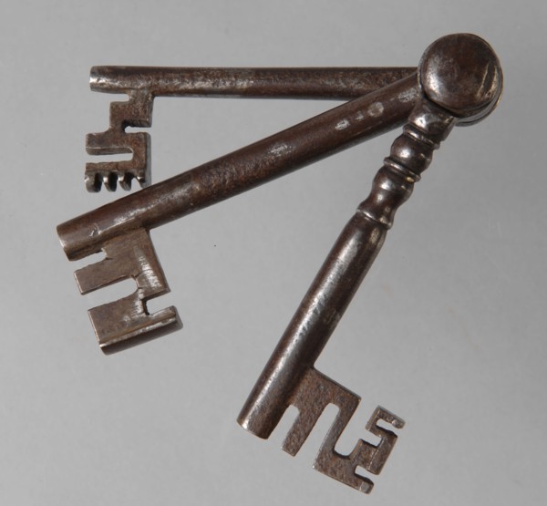 Three different iron keys, consisting of key stems with beards, which are hinged to each other at the top of the handle, key