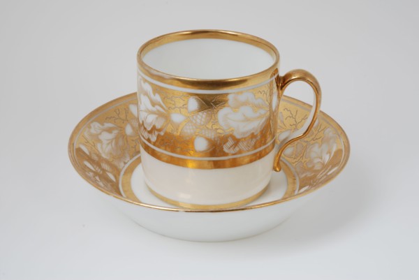 White cup and saucer with gold colored band with acorn and leaf decoration, cup and saucer drinkware tableware holder coffee