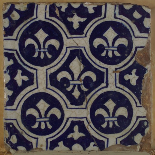 Two-tone tile, blue on white background, four circles with white French lily around central ornament with lily, wall tile