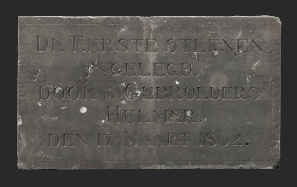 Facade stone with text THE FIRST STONE LOCATED BY THE BROTHERS HELMER DEN 17E MARCH 1862, facing brick first stone building part
