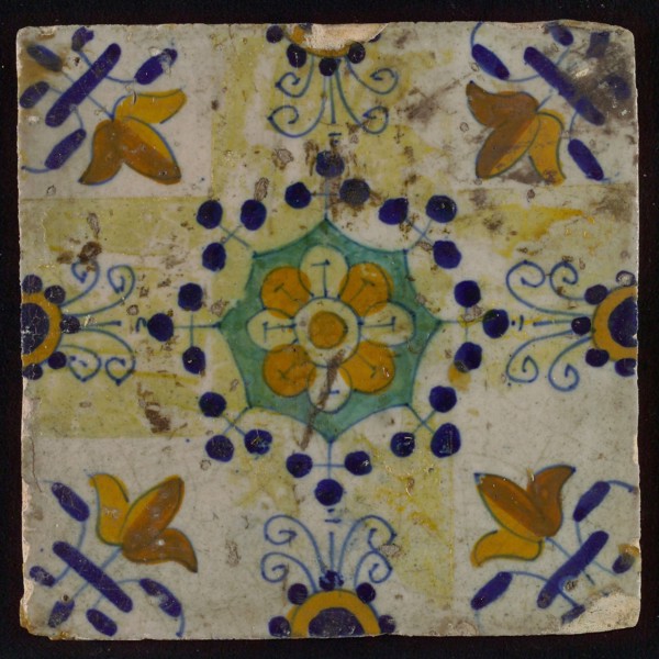 Tile, blue draft, yellow, green and orange on white, central flower within star shape, three-spot around, half rosette, corner