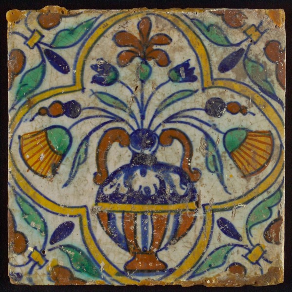 Tile, blue draft, yellow, orange, brown and green on white, centrally flower pot within four-sided frame, corner motif, wall