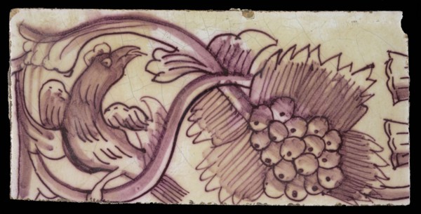 Rectangular edge tile in purple with serpentine decor of leafy tendril, twisted bird to the right, grape bunch, border tile wall