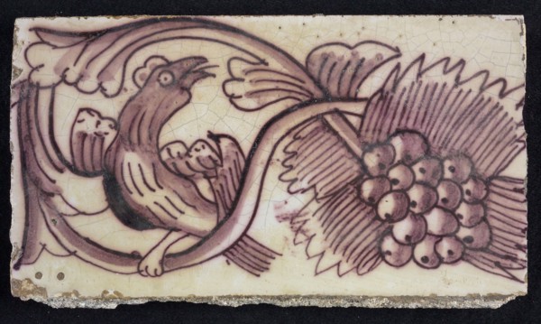 Rectangular edge tile in purple with serpentine decor of leafy tendril, toasted bird to the right, grape bunch, edge tile wall
