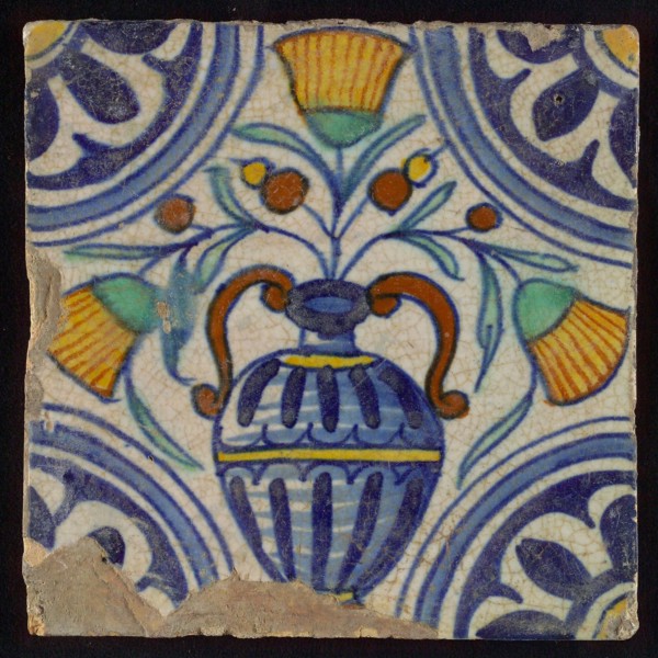 Tile, blue draft, orange, yellow, brown and green on white, central flowerpot with marigolds, corner pattern, rosette, wall tile