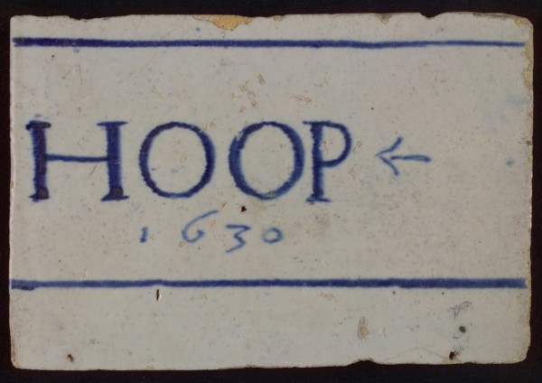 White tile with in blue HOOP and 1630 between horizontal lines, tile picture footage fragment ceramics pottery glaze, baked 2x